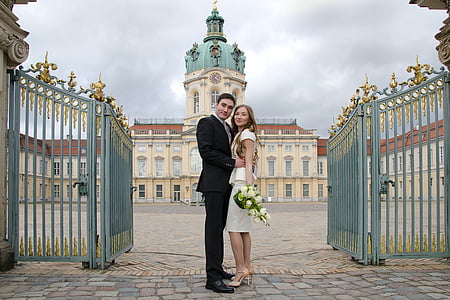 man and woman taking picture standing in front of cathedral during daytime thumbnail