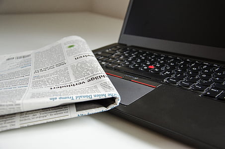 newspaper beside black Lenovo thinkpad thumbnail