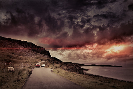 white and red car riding beside body of mountain and ocean during sunset thumbnail