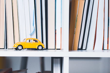 yellow Volkswagen Beetle scale model near book lot thumbnail