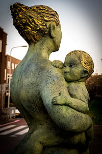 woman carrying a baby statue near brown building thumbnail
