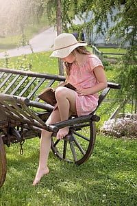 woman sitting on brown wooden wagon while reading book thumbnail