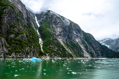 green body of water near mountains thumbnail