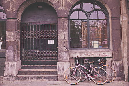 two bicycles against brown building thumbnail