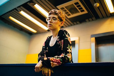 tilt-shift lens photo of woman standing behind handrail of a building thumbnail