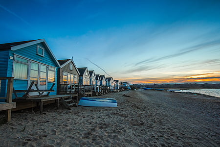 inline blue and brown wooden houses near shoreline under blue sky at daytime thumbnail