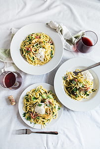 three cooked pasta besides wine glasses on white sheet thumbnail