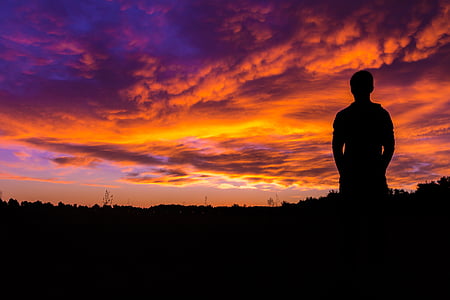 silhouette of man under orange clouds during golden hour thumbnail