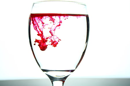 closeup photo of clear glass footed wine cup filled with pink liquid thumbnail
