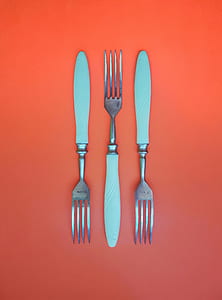 three silver forks on orange surface thumbnail