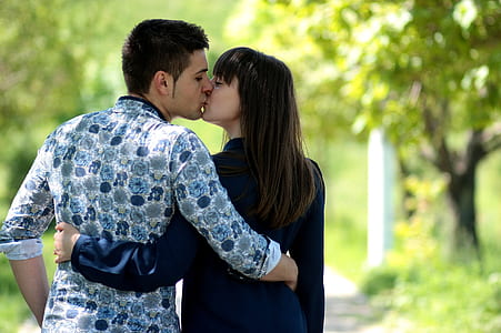 couple kissing while standing on pathway during daytime thumbnail