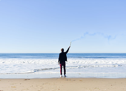 man holding fire cracker on seashore during day time thumbnail