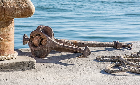 brown metal anchor on gray concrete dock near body of water thumbnail