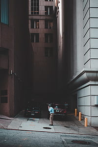 person standing near parked car and building during daytime thumbnail