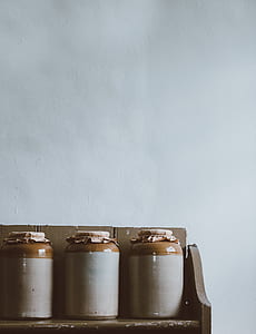 three white-and-brown ceramic canisters on brown wooden shelf thumbnail