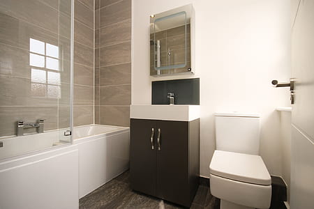 white and black vanity sink beside a toilet bowl thumbnail