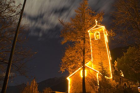 lighted gray concrete building near tree at nightime thumbnail