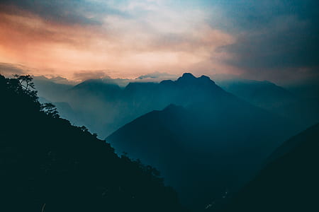 mountain covered with trees under white sky during daytime thumbnail