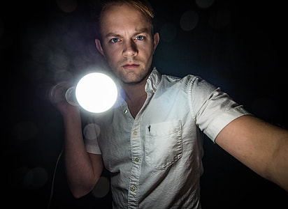 man holding lighted flashslight thumbnail