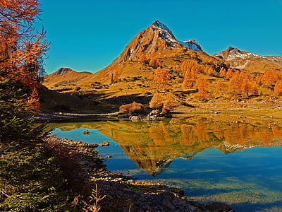 brown mountain near body of water during daytime thumbnail