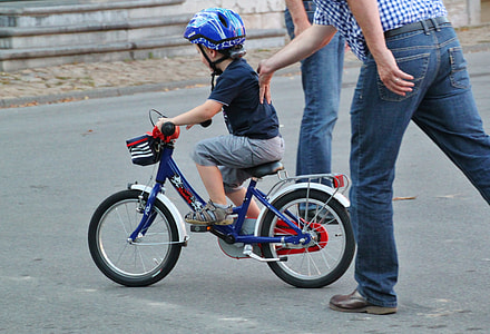 boy riding bike while man pushing him thumbnail