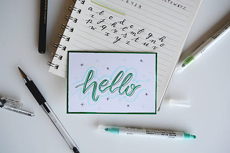 flat-lay photo of notebook, markers, and pens on white surface thumbnail