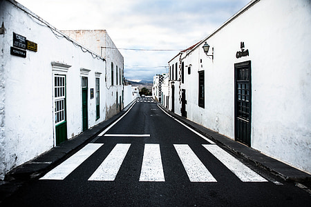 black asphalt road between white painted buildings thumbnail