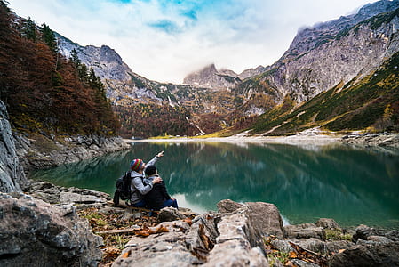 couple sitting on rock near body of water thumbnail