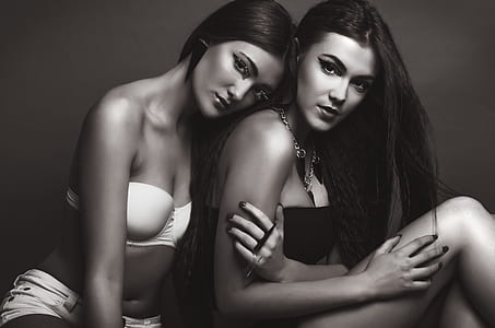 grayscale photo of woman in white padded bra leaning on shoulder of another woman thumbnail