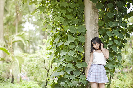 Woman in White Spaghetti Strap Top and Gray Skirt Standing in Front of Tree thumbnail