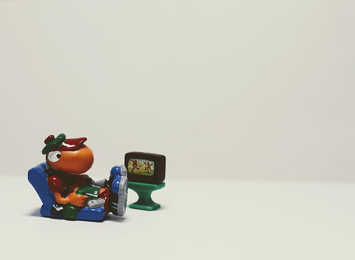 male character sitting on chair while watching TV miniature
