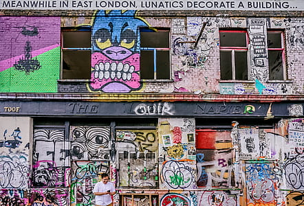 man standing in front of concrete building with graffiti paint thumbnail