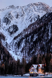 landscape photography of snow covered mountain with two cabins thumbnail