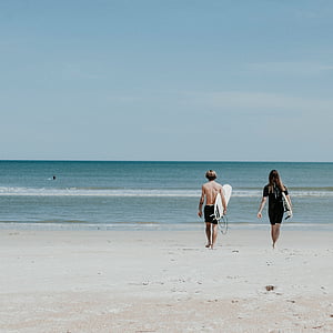 man and woman walking towards sea during daytime thumbnail