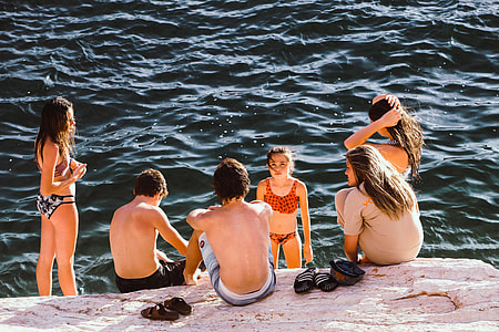 group of people beside sea and rock formation thumbnail