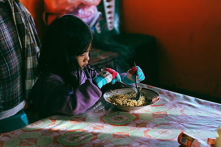 girl holding a spoon sitting beside table thumbnail