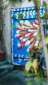 yellow chair beside closed blue and white floral door thumbnail
