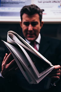 man in black suit reading newspaper thumbnail