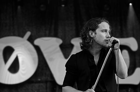 Grayscale Photography of Man Wearing Dress Shirt While Holding Microphone thumbnail