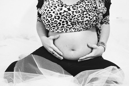 grayscale photography of woman holding her belly in front of mesh net thumbnail
