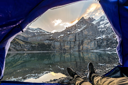 man inside tent taking photo of lake thumbnail