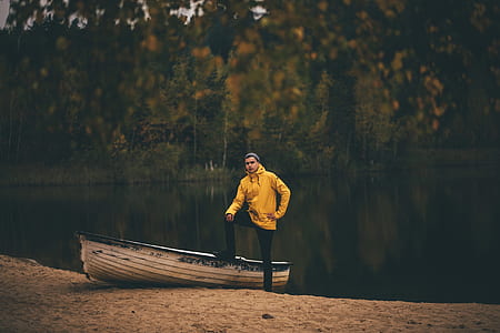 man standing beside canoe and body of water thumbnail