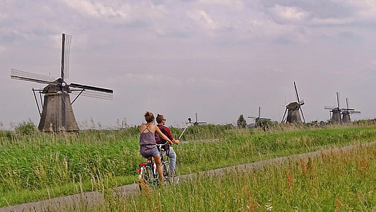 man and woman riding bicycle in between of green grass field thumbnail