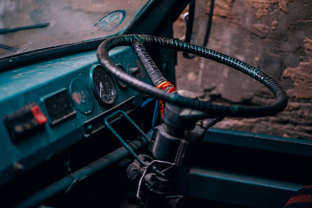 steering wheel beside car window and brown concrete wall thumbnail
