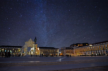 people walking near gray concrete monument under sky full of stars thumbnail