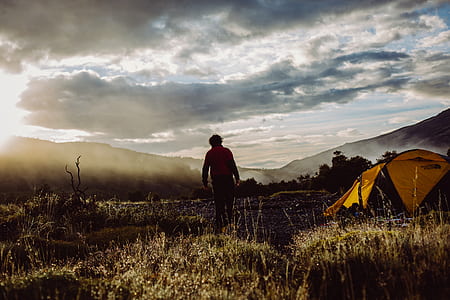 person wearing red jacket standing on field near tent thumbnail