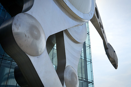 grey metal machine near glass building under grey sky thumbnail