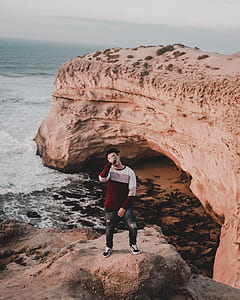 man standing on cliff near sea thumbnail