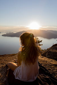 woman sitting on black textile on mountain near lake during daytime thumbnail