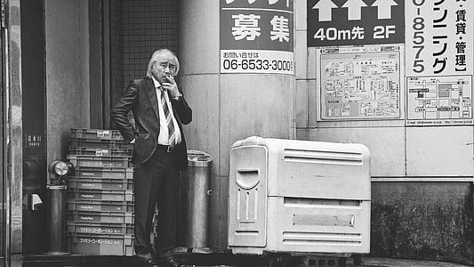 man smoking near building grayscale photo thumbnail